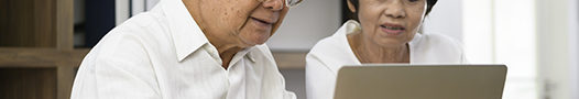 Senior couple typing on laptop